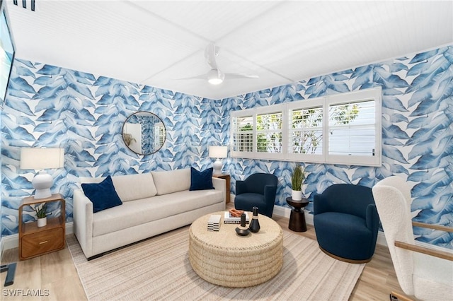 living area featuring baseboards, light wood finished floors, a ceiling fan, and wallpapered walls