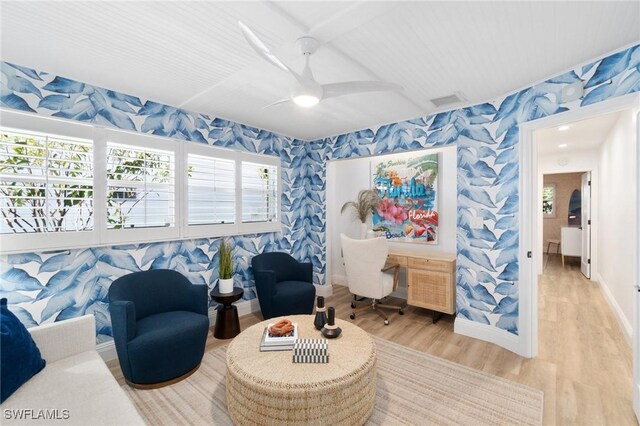 living area with wood finished floors, baseboards, and wallpapered walls