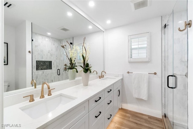 full bathroom with double vanity, wood finished floors, a sink, and visible vents