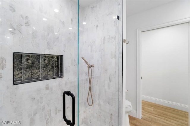 bathroom featuring toilet, a shower stall, baseboards, and wood finished floors