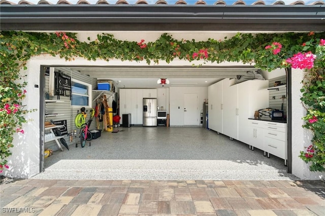 garage with stainless steel fridge and a garage door opener