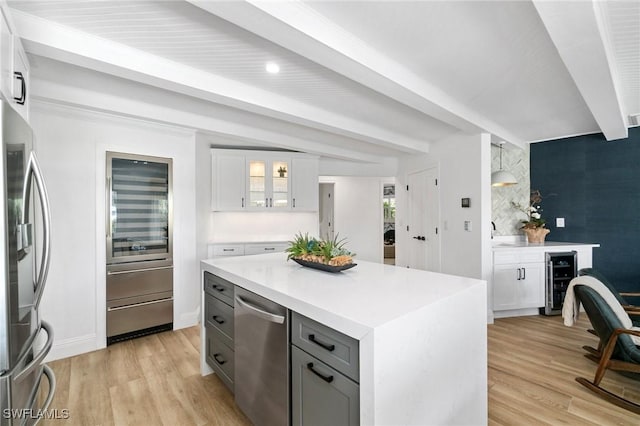 kitchen featuring stainless steel appliances, light countertops, a center island, beamed ceiling, and glass insert cabinets