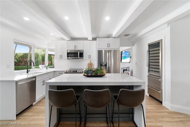 kitchen featuring a sink, white cabinetry, light countertops, appliances with stainless steel finishes, and a center island