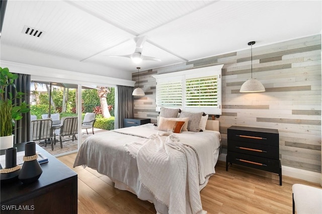 bedroom with wood walls, access to outside, visible vents, and light wood-style flooring