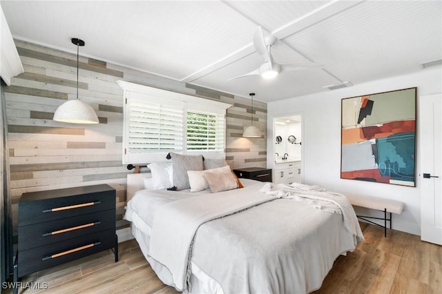 bedroom featuring light wood-style floors, visible vents, ceiling fan, and wooden walls