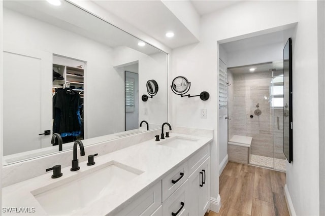 bathroom with a stall shower, a spacious closet, a sink, and wood finished floors