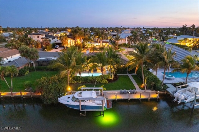 aerial view at dusk featuring a water view and a residential view