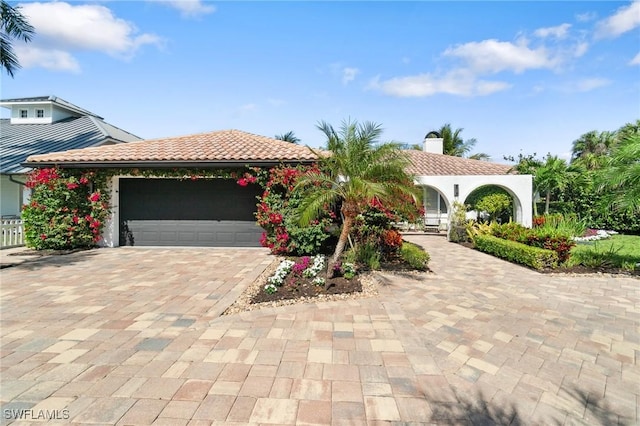 view of front of property featuring decorative driveway, a tiled roof, and an attached garage