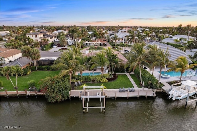 aerial view at dusk featuring a water view and a residential view