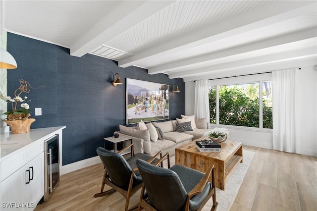 living area featuring light wood finished floors, beamed ceiling, wine cooler, and baseboards