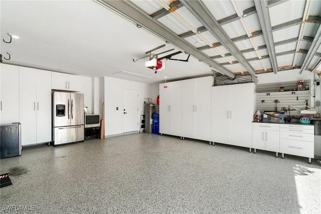 garage with a garage door opener, water heater, and stainless steel fridge with ice dispenser