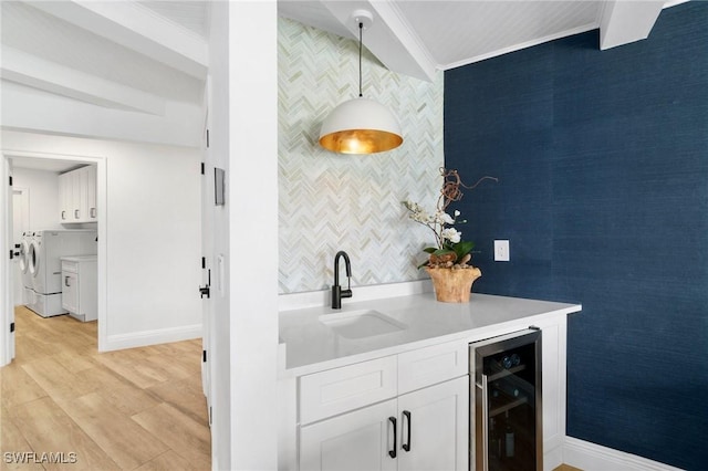 bar with pendant lighting, ornamental molding, a sink, washer and dryer, and beverage cooler