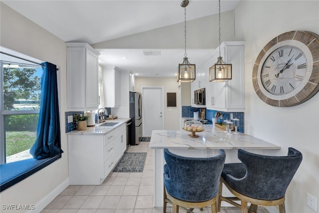 1533 San Marco Rd, Marco Island, FL 34145 - kitchen with white cabinetry, lofted ceiling, light tile patterned floors, stainless steel appliances, and a peninsula