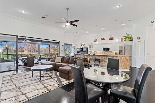 dining space featuring ceiling fan, ornamental molding, dark hardwood / wood-style flooring, and a towering ceiling