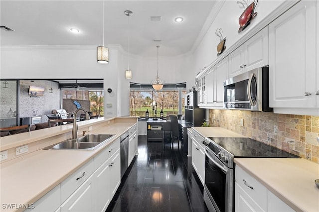 kitchen with sink, appliances with stainless steel finishes, white cabinetry, backsplash, and hanging light fixtures