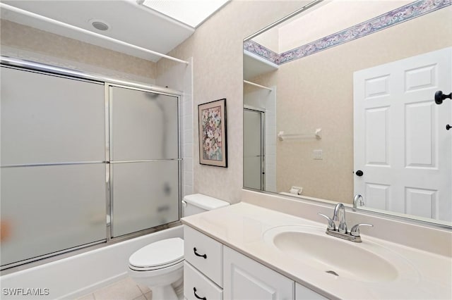 full bathroom with toilet, tile patterned floors, vanity, and bath / shower combo with glass door