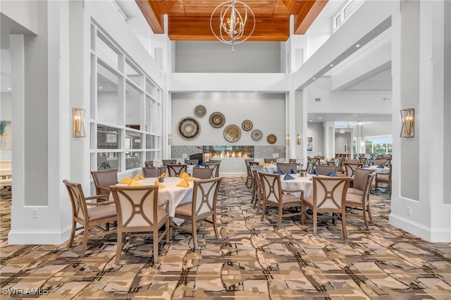 dining space with an inviting chandelier, a towering ceiling, and wood ceiling