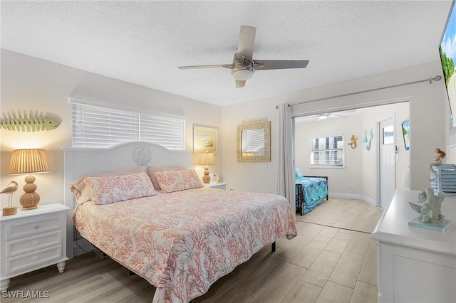 bedroom with ceiling fan, a textured ceiling, and light wood-type flooring