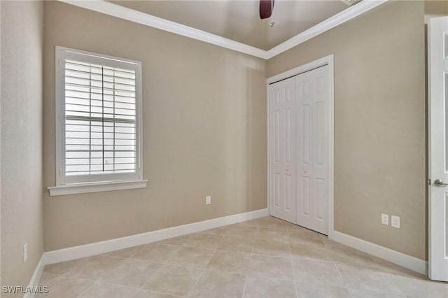 unfurnished bedroom featuring ornamental molding, light tile patterned floors, ceiling fan, and a closet