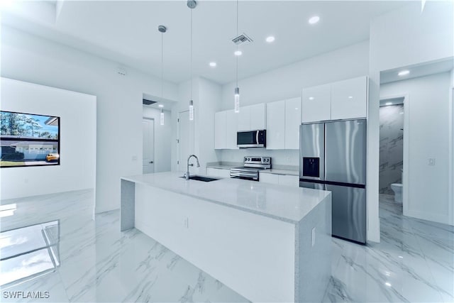 kitchen with sink, a center island with sink, hanging light fixtures, appliances with stainless steel finishes, and white cabinets