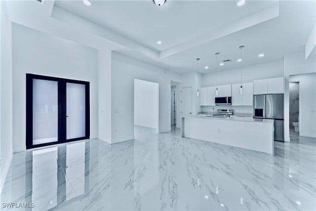 kitchen featuring white cabinetry, appliances with stainless steel finishes, a kitchen island with sink, and decorative light fixtures