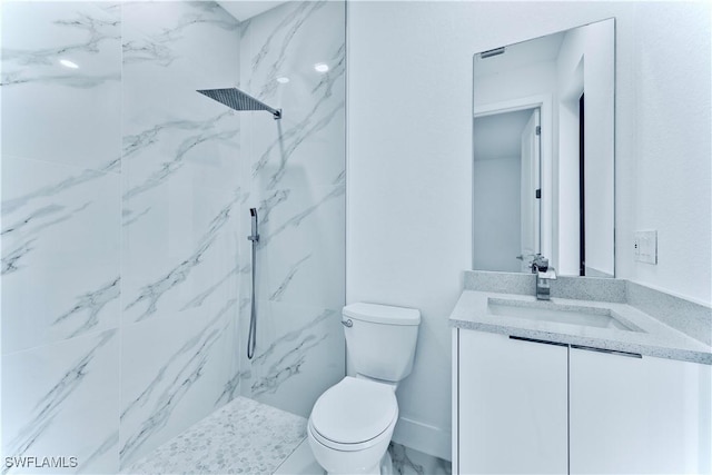 bathroom with vanity, tiled shower, and toilet