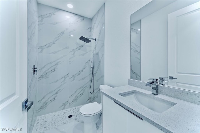 bathroom with vanity, toilet, and tiled shower