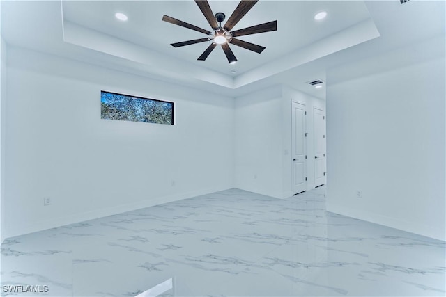 spare room with ceiling fan and a tray ceiling