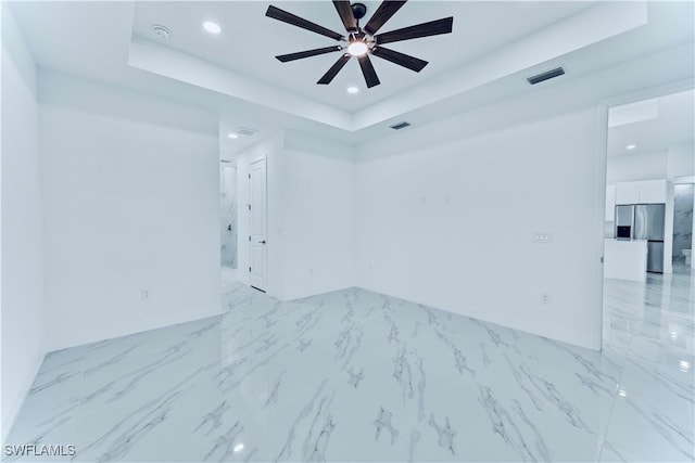 spare room with a raised ceiling and ceiling fan