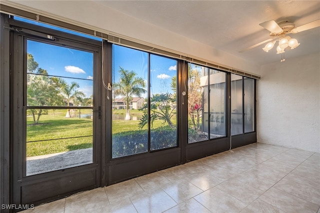 unfurnished sunroom with ceiling fan and a water view