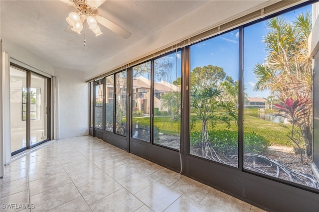 unfurnished sunroom featuring a water view and ceiling fan