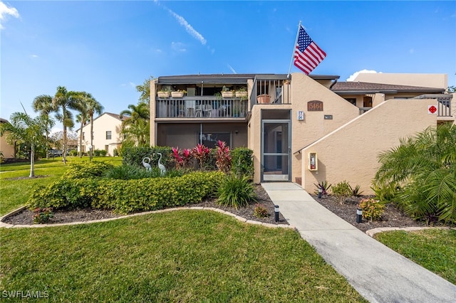 view of front of house featuring a balcony and a front lawn