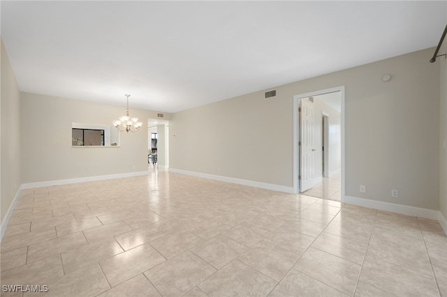 empty room with light tile patterned flooring and a notable chandelier