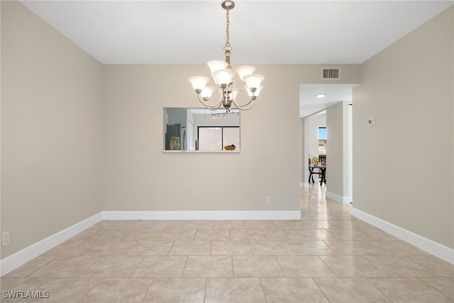 tiled spare room with a healthy amount of sunlight and a notable chandelier