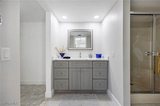 bathroom with a shower with door, vanity, and tile patterned flooring