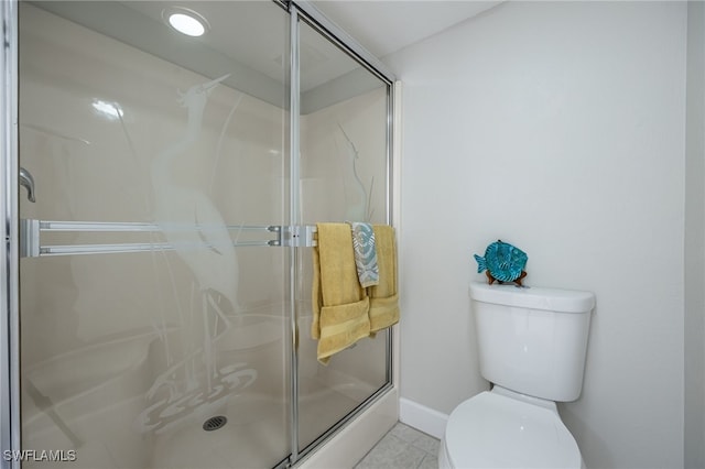 bathroom featuring tile patterned floors, toilet, and a shower with shower door