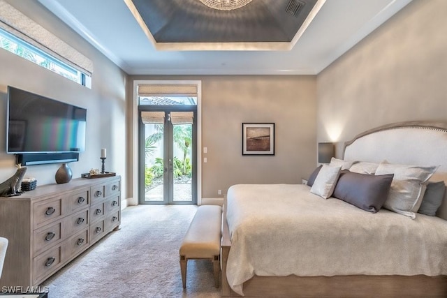 bedroom with access to exterior, a tray ceiling, carpet floors, and french doors