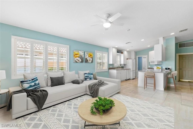 tiled living room featuring vaulted ceiling, ceiling fan, and sink