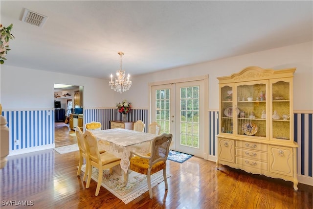 dining space with hardwood / wood-style flooring, french doors, and a chandelier