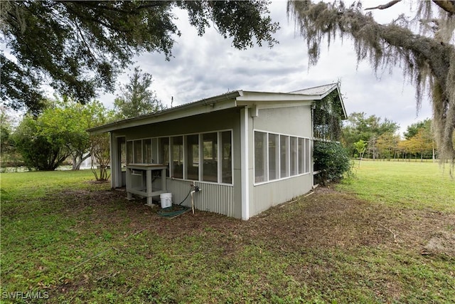 view of side of home with a sunroom and a yard