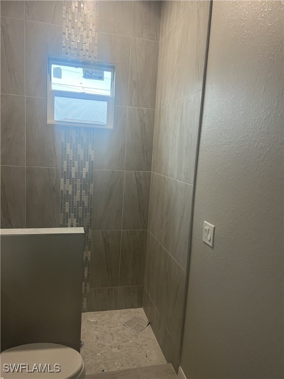 bathroom featuring toilet and tiled shower