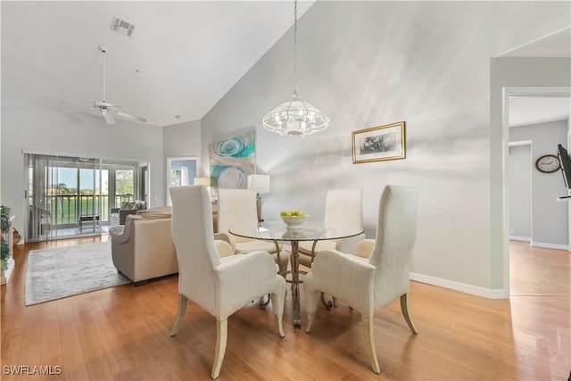 dining space featuring high vaulted ceiling, ceiling fan with notable chandelier, and light hardwood / wood-style floors