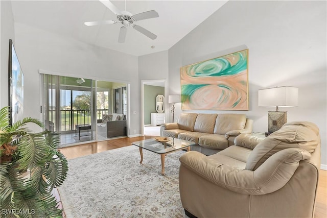 living room with light hardwood / wood-style flooring, ceiling fan, and a high ceiling