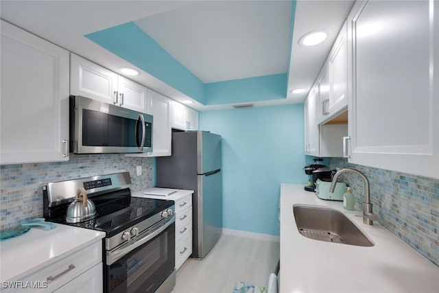 kitchen featuring sink, tasteful backsplash, light wood-type flooring, stainless steel appliances, and white cabinets