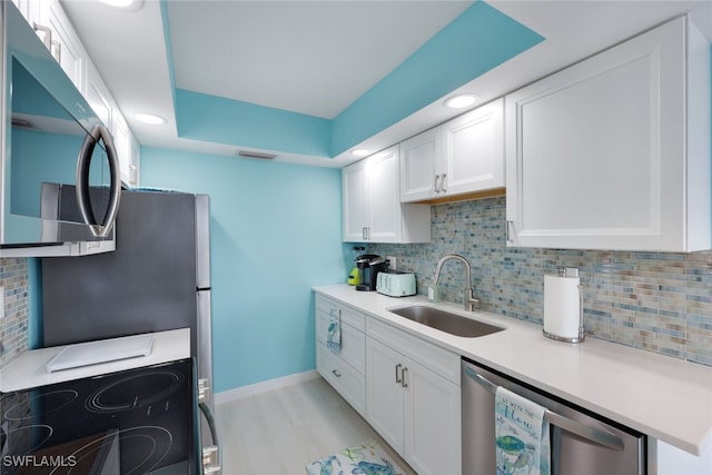 kitchen featuring stainless steel appliances, white cabinetry, sink, and decorative backsplash