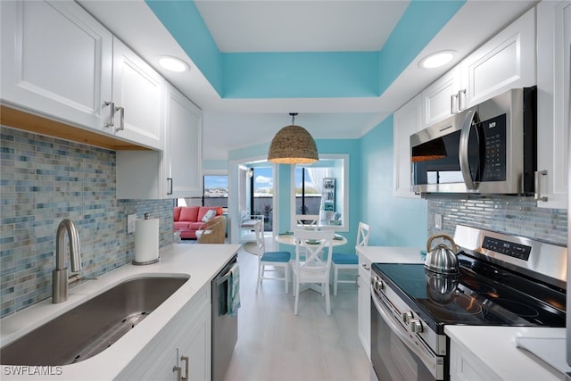 kitchen featuring appliances with stainless steel finishes, decorative light fixtures, sink, and white cabinets