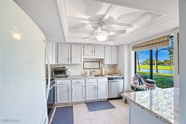 kitchen with a raised ceiling, sink, white cabinets, light stone counters, and stainless steel appliances