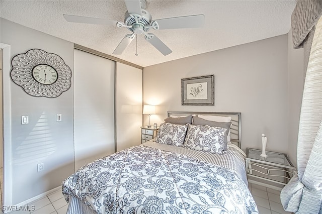 bedroom with light tile patterned floors, a closet, a textured ceiling, and ceiling fan