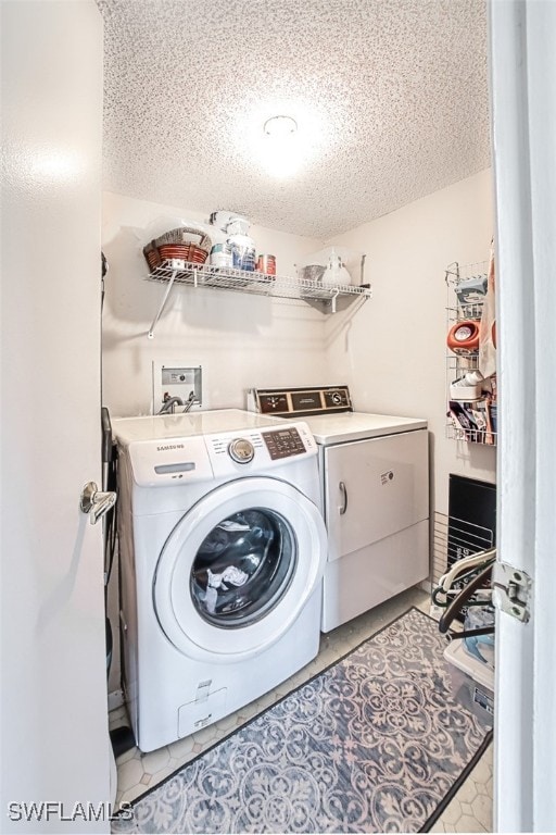 clothes washing area featuring washer and dryer, light tile patterned floors, and a textured ceiling