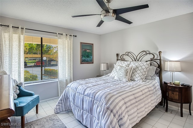 bedroom with ceiling fan, light tile patterned floors, and a textured ceiling